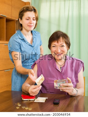 Smiling daughter asking aged mother  the money for minor expenses at home