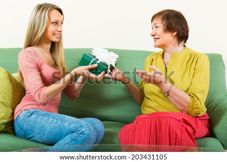Girl congratulating aged mother and giving a present on Mother\'s Day