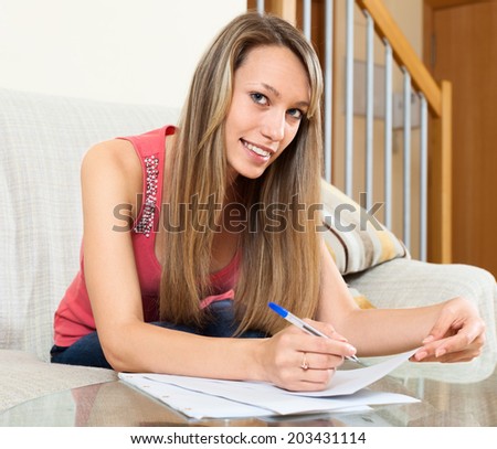 Young woman editing  documents on sofa at table
