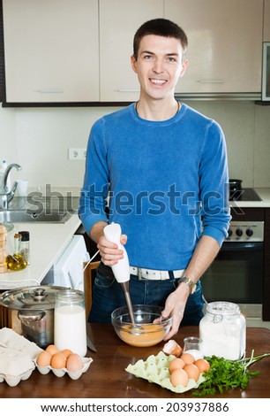 european man cooking omelet with flour in home