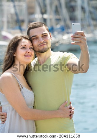 Happy man and woman in summer clothes doing selfie