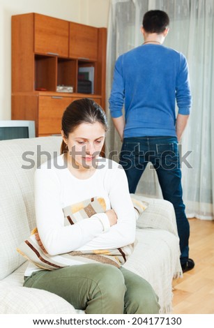 Family quarrel. Sadness woman against standing man at home
