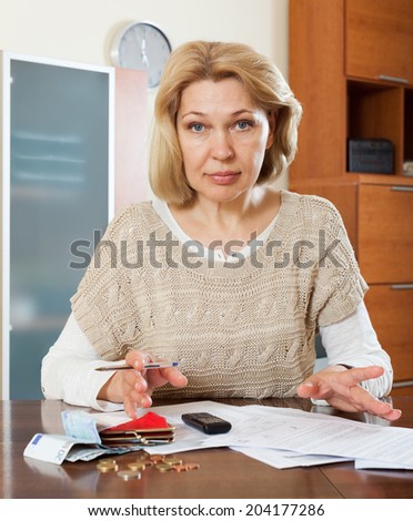 Sad mature woman thinking about the financial issue at  home