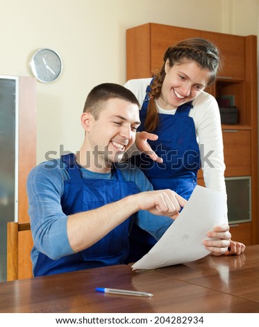 Teamwork of happy workers in uniform looking financial documents at table
