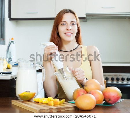 ordinary  woman making fresh milk beverages with blender from mango at domestic kitchen