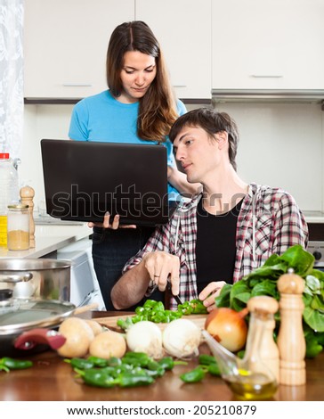 girl shows the new recipe on laptop during dinner cooking