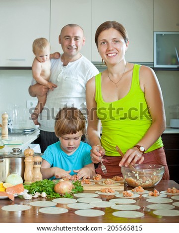 Happy family of four making homemade ravioli stuffed with fish and dough