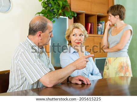 Adult daughter and mature parents having serious talking in home interior