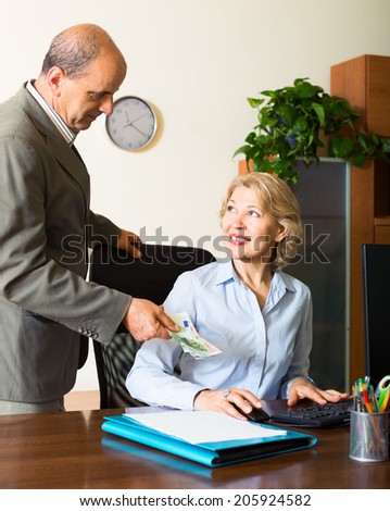 Mature male accountant  paying salary in cash in office