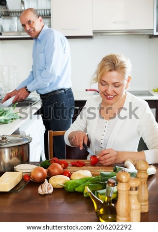 happy mature couple cooking healthy food at home kitchen