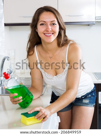 Happy woman cleaning  furniture in kitchen at home