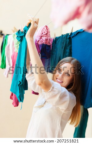 Long-haired housewife drying clothes on clothes-line