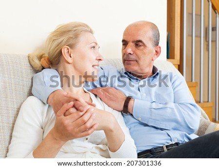 Happy elderly man flirting with mature wife and hug together in home interior