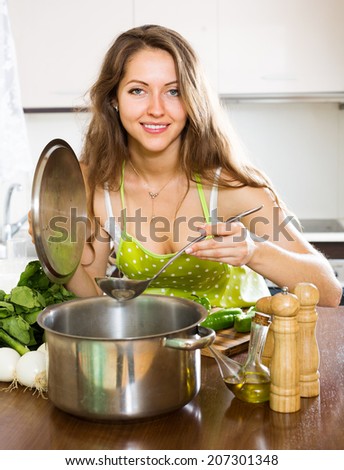 woman in apron cooking  soup in kitchen
