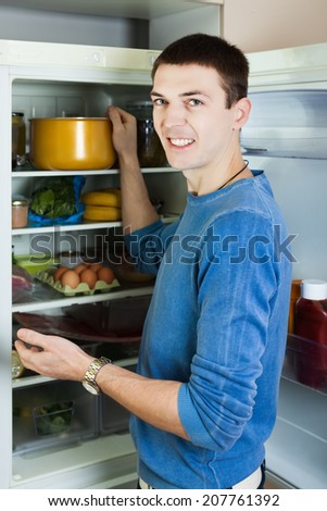 guy searching for something in refrigerator  at home