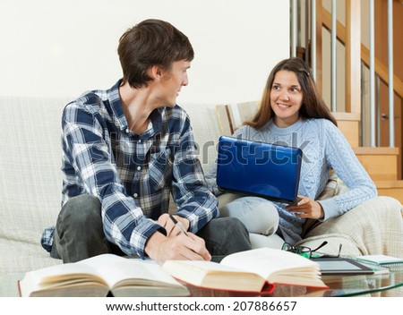 Young student couple at home reading, writing, preparing for the session
