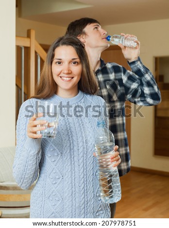 Happy young people drinking clean water in home