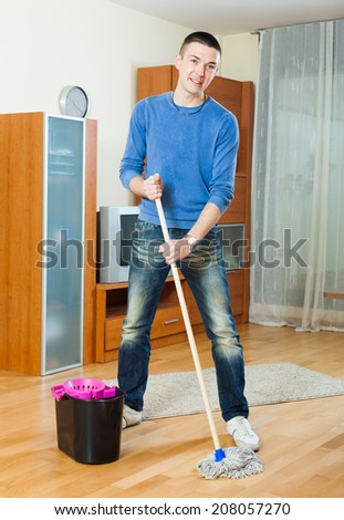 man washing parquet floor with mop in living room at home