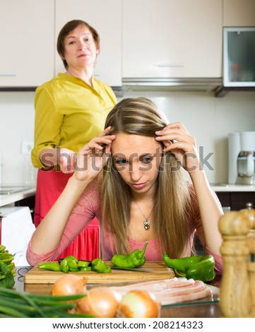 Family quarrel between adult daughter and elderly mother in the kitchen