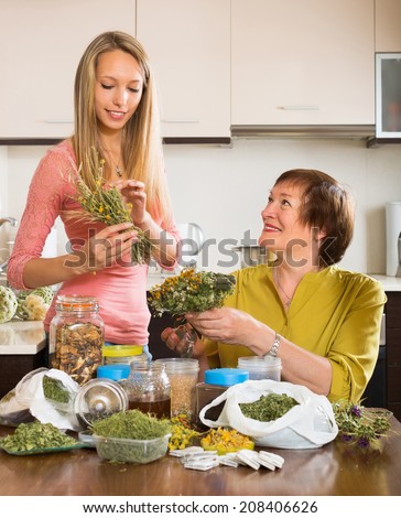Happy mature woman with adult daughter with dried herbs