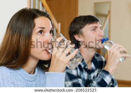 Young couple in the room drinking bottled water