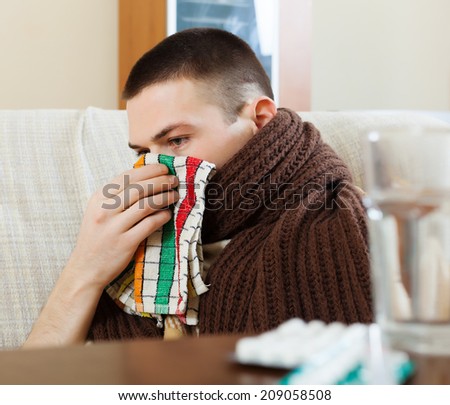 Ilness man in scarf using handkerchief in home