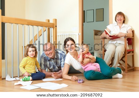 Happy couple with their offspring and grandmother on floor at home