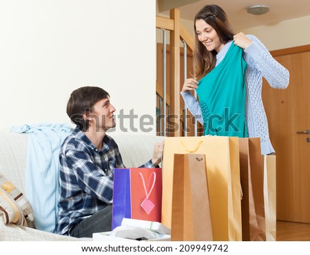 Happy  woman shopper and man with clothing and shopping bags in home