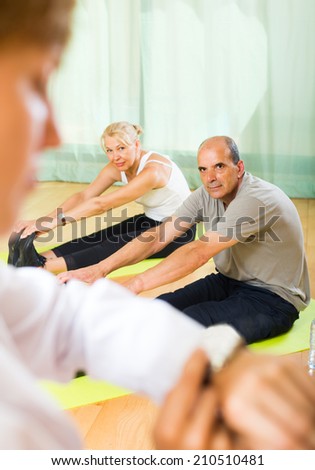 Medical staff watching yoga class for seniors indoor. Focus on man