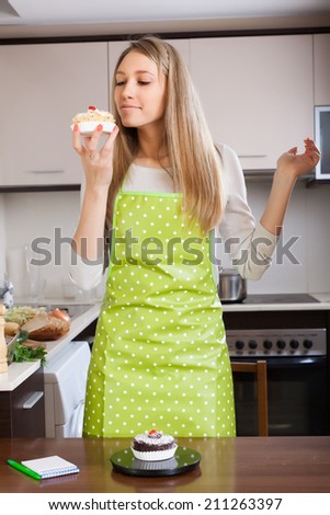 Woman in apron weighing cakes on kitchen scales at kitchen