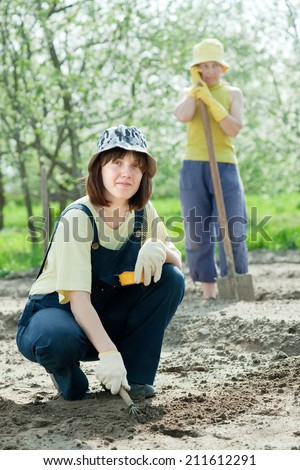 Happy women works at vegetables garden in spring