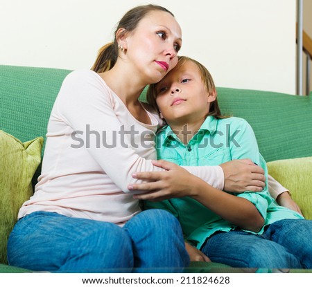 middle-aged mother consoling sad teenage son at home