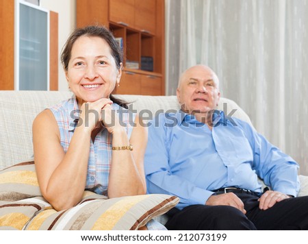 cheerful mature woman against elderly man in home interior