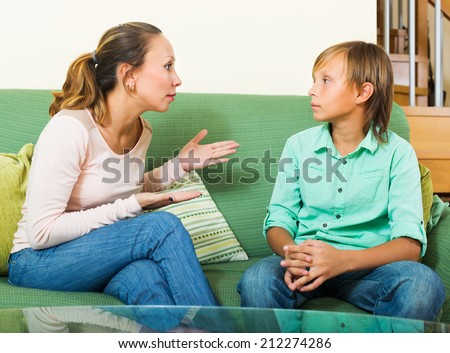 Serious middle-aged  mother and  teen boy talking in home interior