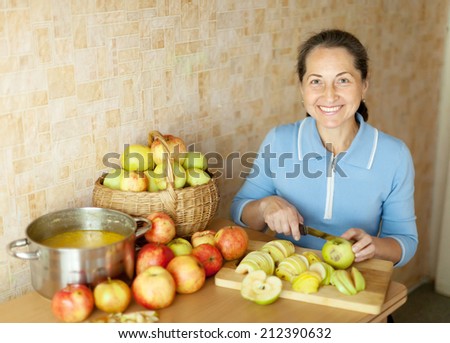 Woman cuts apples for apple jam in kitchen