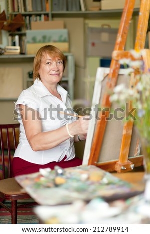 Female artist paints a picture on canvas with oil paints