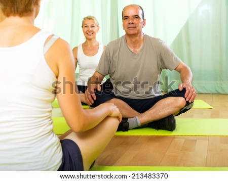 Young  yoga instructor showing asana to elderly attenders