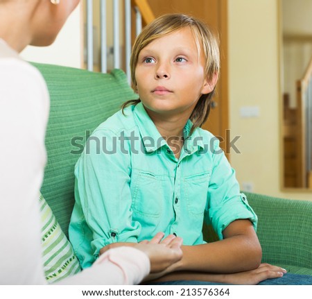 Serious  mother and  teen boy talking in home interior. Focus on son