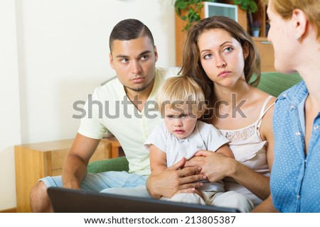 unhappy parents and baby  sitting in front of social worker