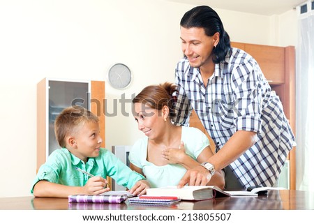 Serious couple with clever schoolboy  doing homework in a home