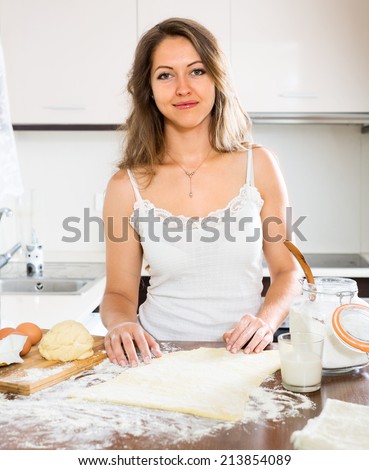 beautiful woman preparing cakes of dough at kitchen