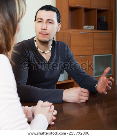 Serious man and woman talking in home interior