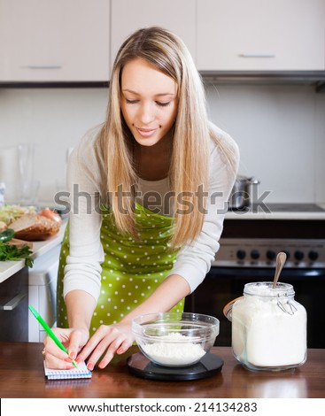 Housewife  weighing floor on kitchen scales at home