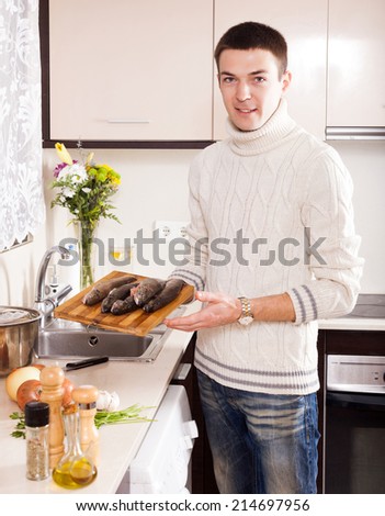 Smiling guy cooking  trout at home