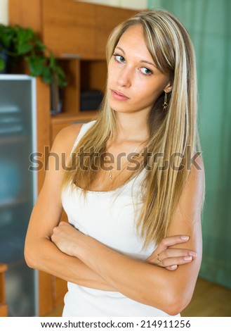 Blonde sad young woman in the living room at home
