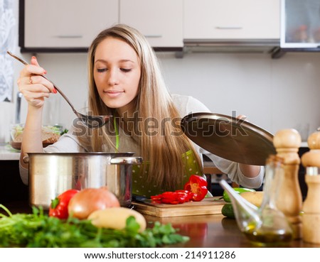 Blonde woman with ladle cooking soup in home kitchen