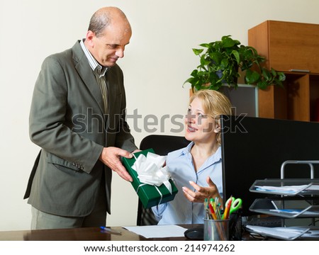 Elderly man giving a gift to his colleague in the office