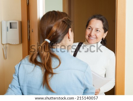 Mature woman polling among people at home  door