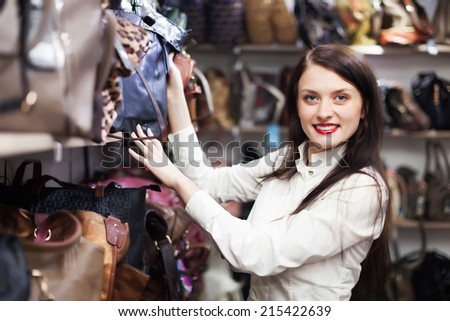 Young woman choosing leather bag at store