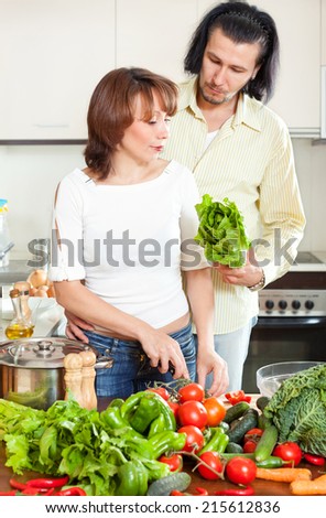 Happy couple cutting the celery for salad in kitchen